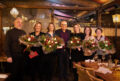 Sechs Jubilaren werden auf der Weihnachtsfeier geehrt. Sie stehen in einer Reihe, der Geschäftsführer steht in der Mitte. Fünf Personen halten einen weihnachtlich geschmückten Blumenstrauß.